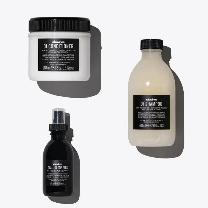 Variety of vegan haircare products including shampoos and conditioners on a wooden surface with green plants